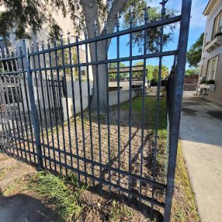 A view of a metallic fence next to a pathway, defining the boundary of a property.