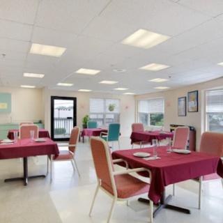 An empty dining room with tables and chairs covered in red tablecloths.
