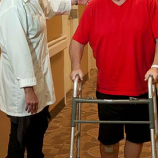A doctor assists a patient using a walker in a healthcare facility.