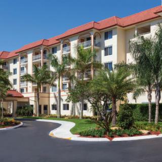 A modern apartment building with well-maintained landscaping and palm trees on a sunny day.