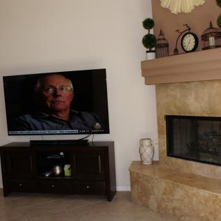 A cozy living room with a television and a stone fireplace.