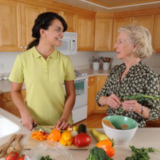 Two women chatting while preparing vegetables in the kitchen.