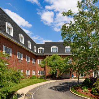 A brick building with a landscaped driveway and a clear blue sky.
