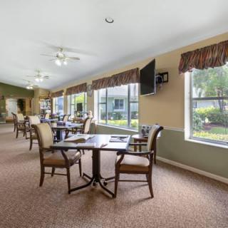 A spacious dining area with tables and chairs, filled with natural light from large windows.
