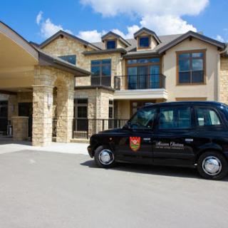 A black taxi parked in front of a stylish residential building on a sunny day.