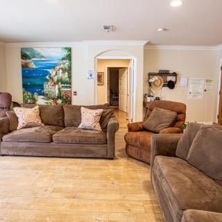 A cozy living room featuring brown sofas, an armchair, and a scenic painting on the wall.