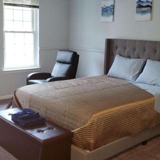A cozy bedroom with a bed, chair, and window.