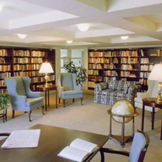 A cozy library room with bookshelves, comfortable armchairs, and a globe on a table.