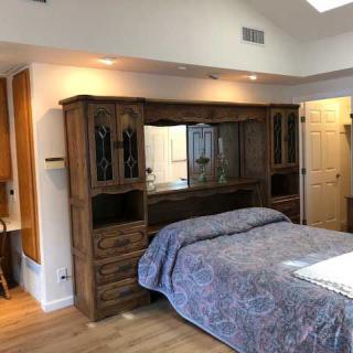 A cozy bedroom featuring a bed with wooden cabinets and a quilted bedspread.