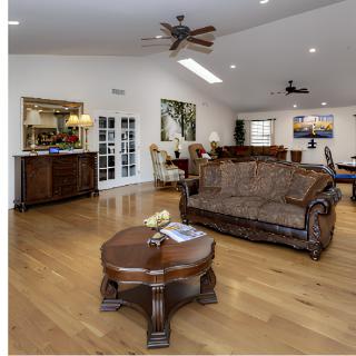 Spacious and elegantly furnished living room with a hardwood floor and ceiling fan.