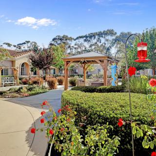 A beautifully landscaped garden with a gazebo, colorful flowers, and well-maintained pathways.