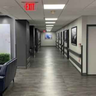 A modern hallway with art on the walls and an exit sign at the ceiling.