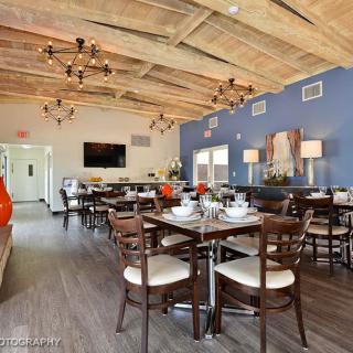 A cozy restaurant interior with a wooden ceiling, neatly arranged tables, and elegant chandeliers.