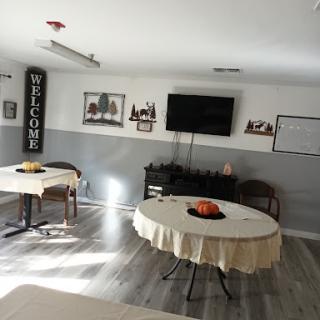 A welcoming interior space featuring round tables and a TV, designed for gatherings or meetings.