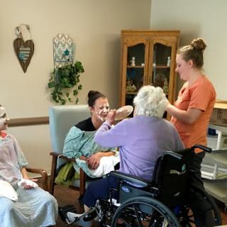 Caregivers engaging with elderly residents during a group activity in an assisted living facility.