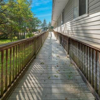 A long wooden ramp with handrails on a sunny day, casting shadows along the pathway.