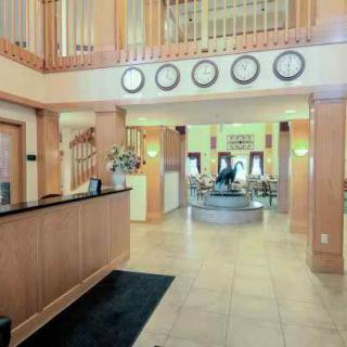 A modern hotel lobby with a reception desk and several clocks displaying different time zones.