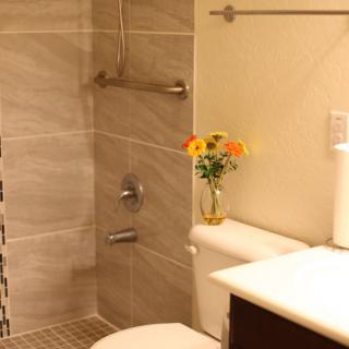 A modern bathroom with a walk-in shower and decorative flowers on the toilet.
