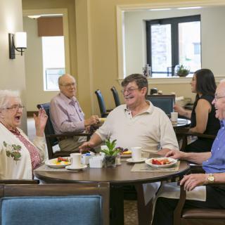 A group of seniors enjoying a meal and conversation at a community dining area.