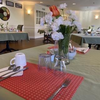 A dining table set with a vase of flowers and neatly arranged utensils in a restaurant.