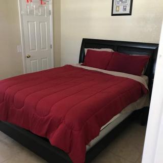 A neatly made bed with red bedding in a simple bedroom.