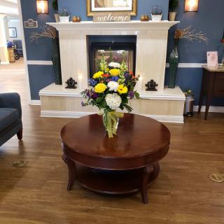 A cozy living room with a beautifully arranged flower bouquet on the coffee table in front of a fireplace.