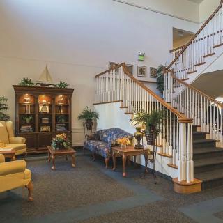 A cozy living room with traditional decor, featuring a wooden staircase and elegant furniture.