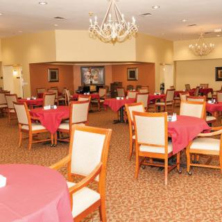 An elegant dining room with neatly arranged tables and chairs, featuring chandeliers.