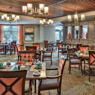 An elegant dining room with neatly arranged tables and chairs, adorned with chandeliers.