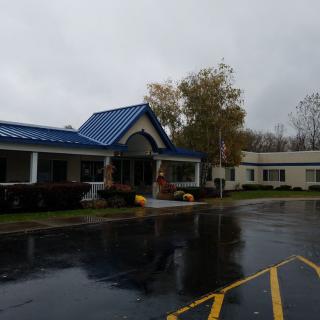 A rainy day scene featuring a building with a blue roof and an adjacent parking lot.
