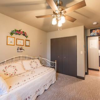 A cozy bedroom featuring a daybed, ceiling fan, and decorative artwork on the walls.