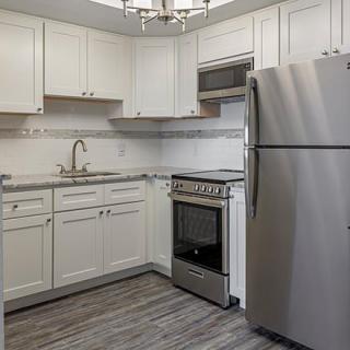 A modern kitchen with white cabinets and stainless steel appliances.