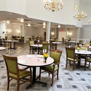 An empty dining area with multiple tables and chairs, decorated with chandeliers.