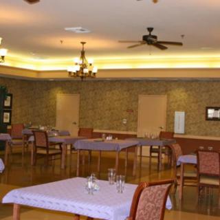 A cozy dining area with neatly arranged tables and chairs, illuminated by soft lighting and a ceiling fan.