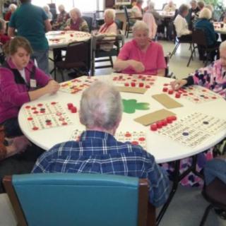 A group of seniors playing a game at a round table in a community setting.