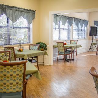 A cozy dining area featuring tables and chairs with natural light streaming through the windows.