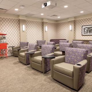 A cozy home theater room with plush seating and a popcorn machine for an enhanced movie-watching experience.