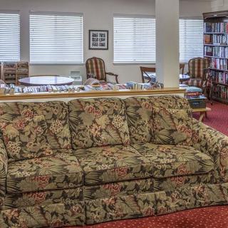 A cozy library seating area with a floral-patterned sofa and bookshelves.