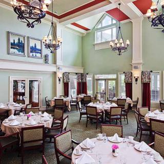Elegant dining room with high ceilings, chandeliers, and neatly arranged tables.