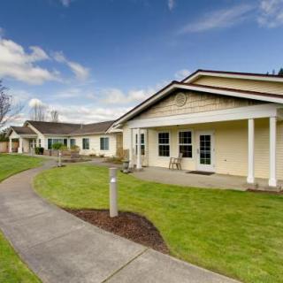 A scenic view of a modern residential building with a well-maintained lawn and pathway under a clear blue sky.