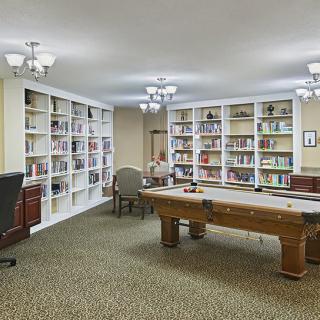 A cozy library with bookshelves and a large table in the center.
