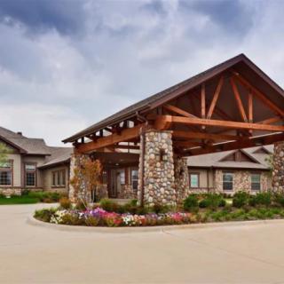 A scenic view of a building entrance with stone pillars and landscaped flowers.