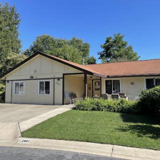 A charming single-story house with a well-maintained front yard and clear blue skies.