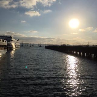 A serene sunset over a calm body of water, with boats docked near a pier.