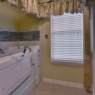 A bathroom with a walk-in bathtub and a window with blinds and curtains.