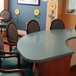 A waiting room with a curved reception desk, chairs, and sunflower wall decorations.