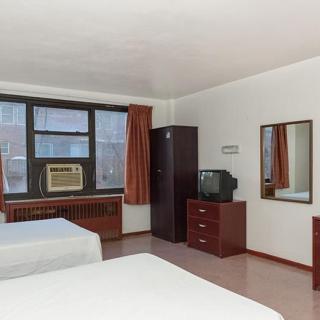 A modest hotel room with two beds, a TV, a mirror, and an air conditioner.