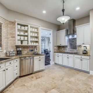 A modern kitchen featuring white cabinets, stainless steel appliances, and a brick backsplash.