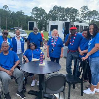 A joyful gathering of community members in blue shirts, enjoying an outdoor event together.