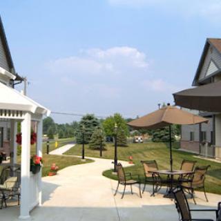 A serene outdoor space featuring a pathway, seating, and well-kept landscaping under a clear blue sky.